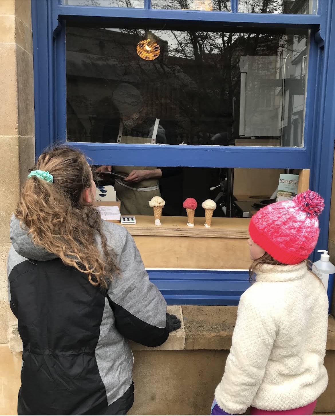 Two children in hats and winter coats queueing outside the shop